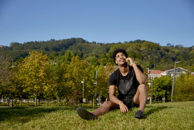 Portrait of smiling young man sitting on plants against sky