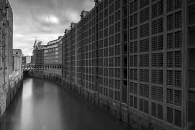 Canal amidst buildings in city against sky