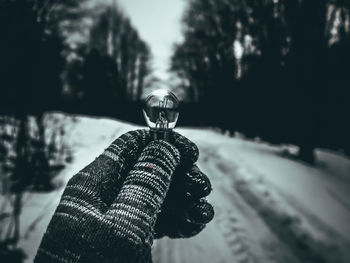 Close-up of hand holding light bulb against sky