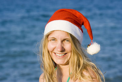 Portrait of young woman in santa hat on beach