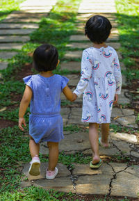 Rear view of sisters walking on footpath at park