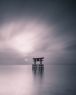 Torii gate in sea during sunset