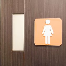 Close-up of female restroom sign on wooden door