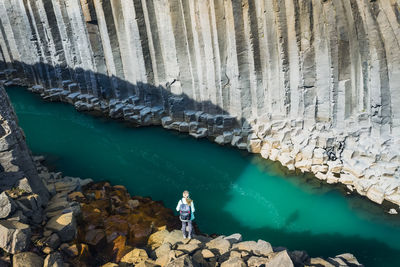 High angle view of man standing on rock by lake