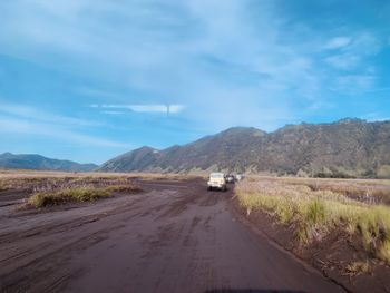 Cars on road by land against sky