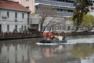 People on boat in river against buildings in city
