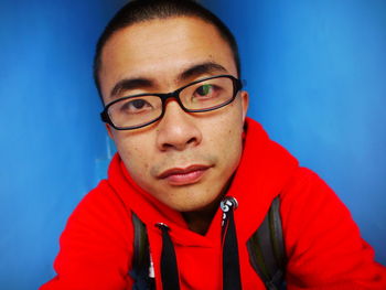 Close-up portrait of man against blue wall