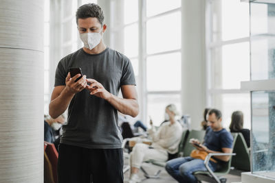 Man wearing mask using mobile phone at airport