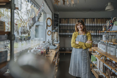 Smiling saleswoman with arms crossed standing in zero waste store