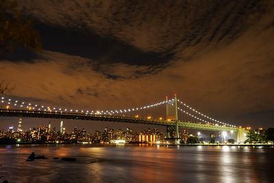 Illuminated bridge over river at night