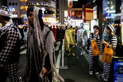 People standing on illuminated city street at night