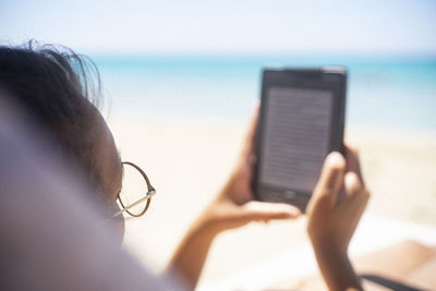 Reading on an e-book at the beach on crete