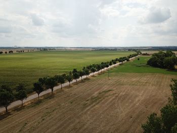 Aerial view of country road by agricultural field against sky