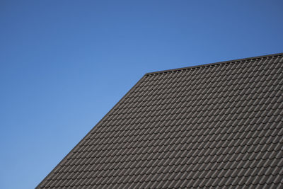 Low angle view of building roof against clear blue sky