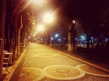 Empty road along illuminated street lights at night