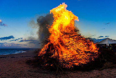 Bonfire in sea against sky at sunset