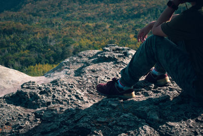 Midsection of man sitting on rock