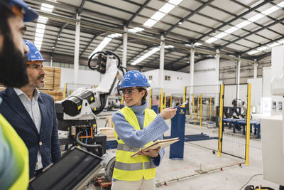 Smiling engineer gesturing colleagues in factory