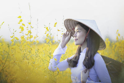 Woman standing by yellow flowers on field