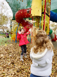Happy young girl throwing leaves against play ground 