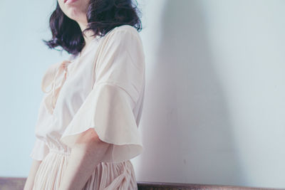 Midsection of woman standing against white wall