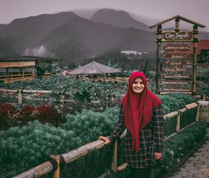 Portrait of smiling woman standing against mountain range