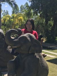 Full length of smiling young woman against trees