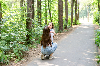 Full length of happy woman standing on footpath amidst trees in forest