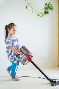 Cute little girl cleaning wooden floor with vacuum cleaner