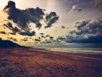 Scenic view of beach against cloudy sky