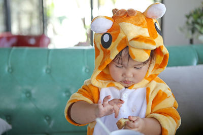 Full length of cute baby girl eating the bread on table