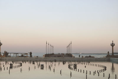 Pier on sea against clear sky during sunset