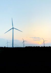 Silhouette windmill on field against sky during sunset