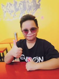 Portrait of boy wearing sunglasses sitting on table