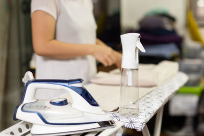 Housewife with bottle spray foggy for iron clothes on ironing board