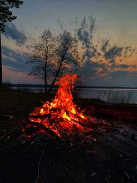 Bonfire on field against sky at sunset