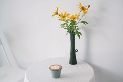 Close-up of flowers in vase against wall