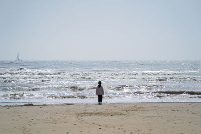 Rear view of man on beach against sky