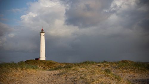 Lighthouse on street amidst buildings against sky