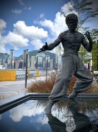 Statue by fountain against sky in city