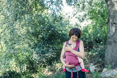 Mother carrying baby against trees