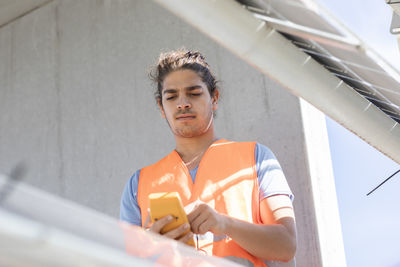 Young male engineer with device working outside