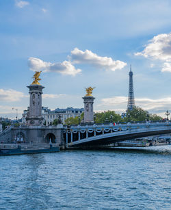 Bridge over river against cloudy sky