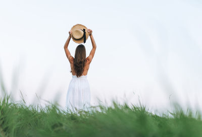 Young long hair woman in white dress with straw hat in sunset field. sensitivity to nature concept