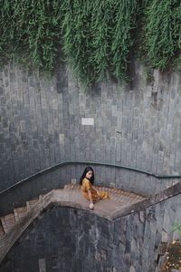 High angle view of woman sitting on stone wall by staircase
