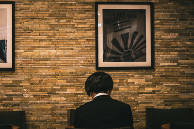 Rear view of man against brick wall