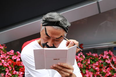 Man holding smart phone while standing on laptop