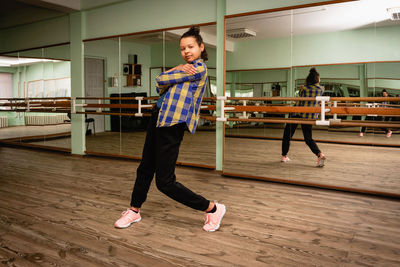 Full length of young black woman dancing alone in choreography hall with mirrors