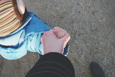 Cropped image of father holding hand of son on beach