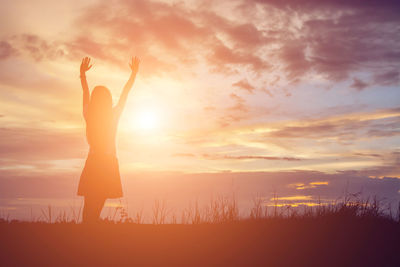 Silhouette woman standing on field against sky during sunset